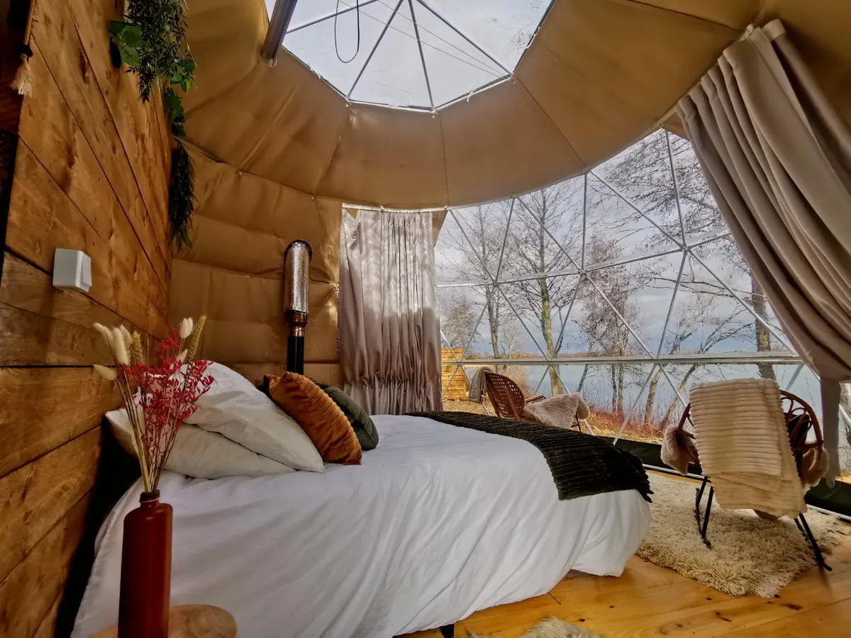 Chambre d'un dôme géodésique aménagée avec vue sur le lac